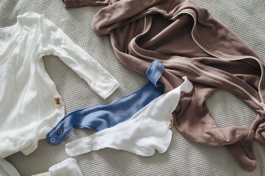 Newborn clothes laid out on a bed